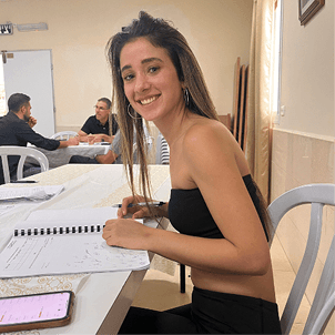 טל יושבת ולומדת עם מחברת